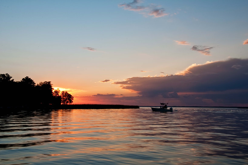 Lake photo at sunset with fishing boat on lake