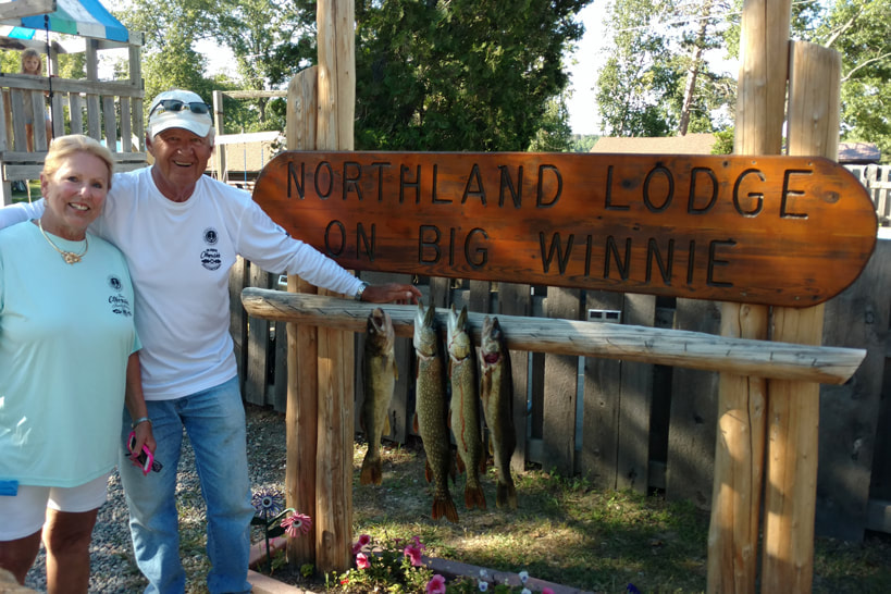 Couple with their walleye at the Northland Lodge sign